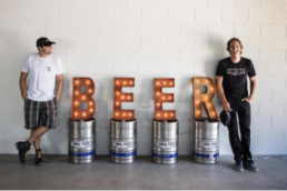 2 guys next to a beer sign