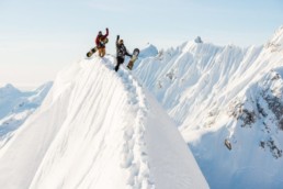 two snowboarders on tip of a snowy mountain