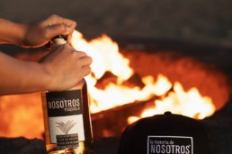 nosotros bottle and hat next to campfire